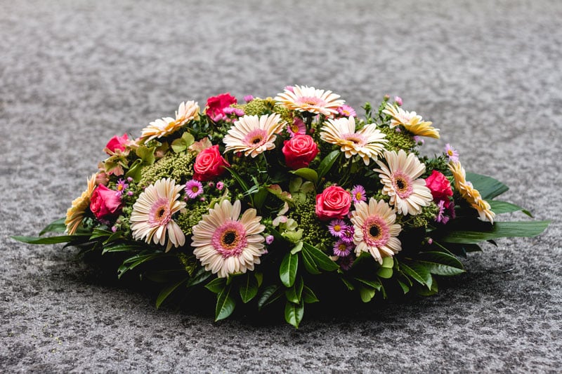 Zoom sur un coussin de fleurs posé sur une pierre tombale