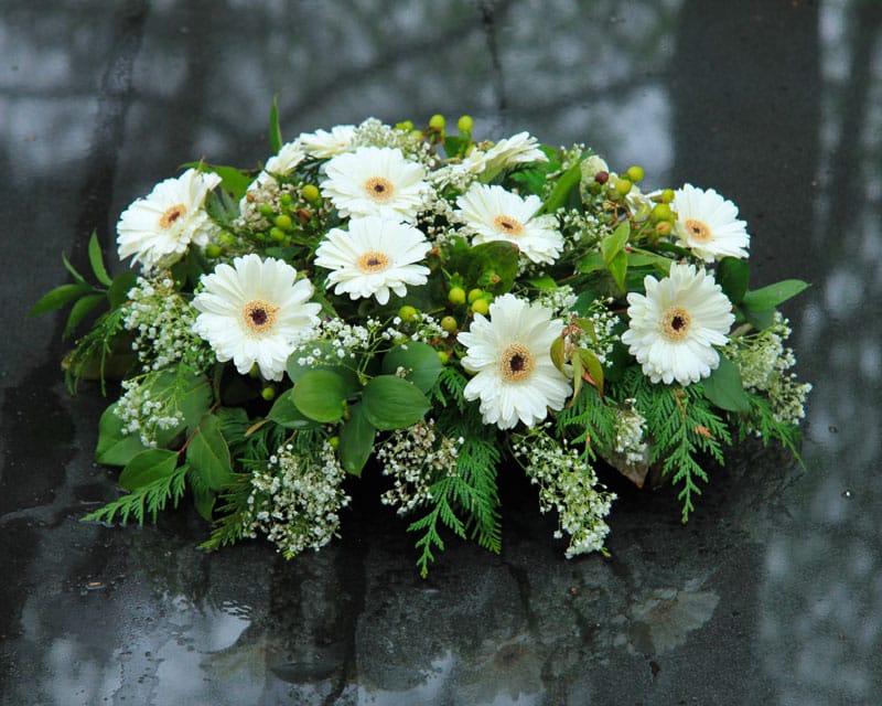 Coussin de fleurs déposé sur une pierre tombale